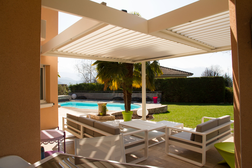 Photo de pergola bioclimatique propre au-dessus d’un salon de jardin par temps ensoleillé

