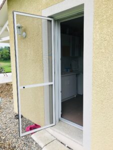 Porte équipée d’une moustiquaire battante pour empêcher l’entrée des moustiques